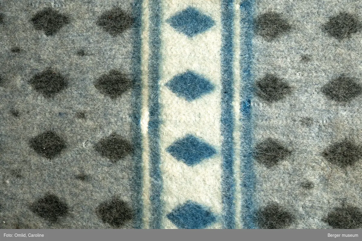 En prøve. Teppe i snipp-mønster . Mønsteret blir brutt av samme mønsterbord, rammet inn av to linjer og  i en annen farge.