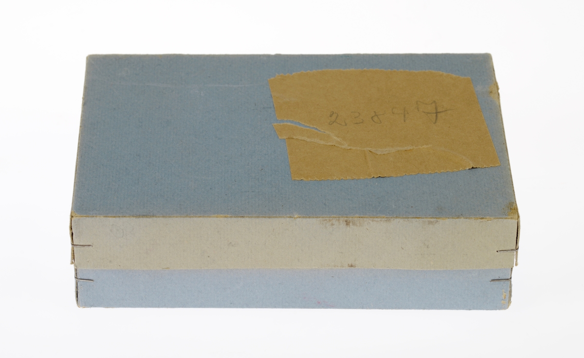 Et kjøkkensett som er montert i en liten pappeske med lokk. Settet er trolig fabrikkprodusert. Gjenstandene er undernummerert 01-10.
FTT.54457.01: En kasserolle med lokk laget av blikk. I hver side av kasserollen er det relativt store svartmalte håndtak av metall, og på lokket er det en treknott som også er svartmalt. Håndtakene og knotten er loddet på. Kasserollen er trolig valset.
FTT.54457.02-03: To identiske tallerkener laget av blikk. De er runde med en bred rand.
FTT.54457.04-05: To identiske kniver laget av metall, og de er antageligvis støpt. Håndtaket har prikker langs kanten som står opp fra metallet, og i midten er det en opphøyet stripe av metall. Knivbladet er relativt bredt og avrundet i tuppen. 
FTT.54457.06-07: To identiske skjeer laget av metall, og de er antageligvis støpt. Håndtaket har prikker langs kanten som står opp fra metallet, og i midten er det en opphøyet stripe av metall. 
FTT.54457.08-09: To identiske gafler laget av metall, og de er antageligvis støpt. Håndtaket har prikker langs kanten som står opp fra metallet, og i midten er det en opphøyet stripe av metall. Gaflene fire tenner.
FTT.54457.10: Esken der gjenstandene 01-09 er montert i. Esken og lokket er laget av papp og er stiftet i hjørnene. Esken er grå og blå på farge. Langs kanten inni esken er det klippet ute en tungekant. I bunnen er det en rød papplate der det er klippet ut hull for montering av de ulike gjenstandene.