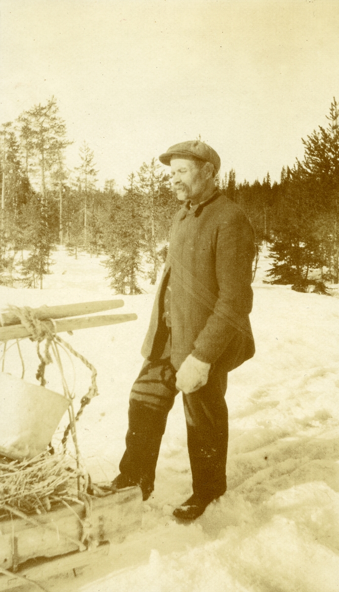 Mann stående i snøen m/slede el. lign. framfor seg i Galåsen. Lars Olsen Storbrenna (Bjørkli) (1868 - 1956)