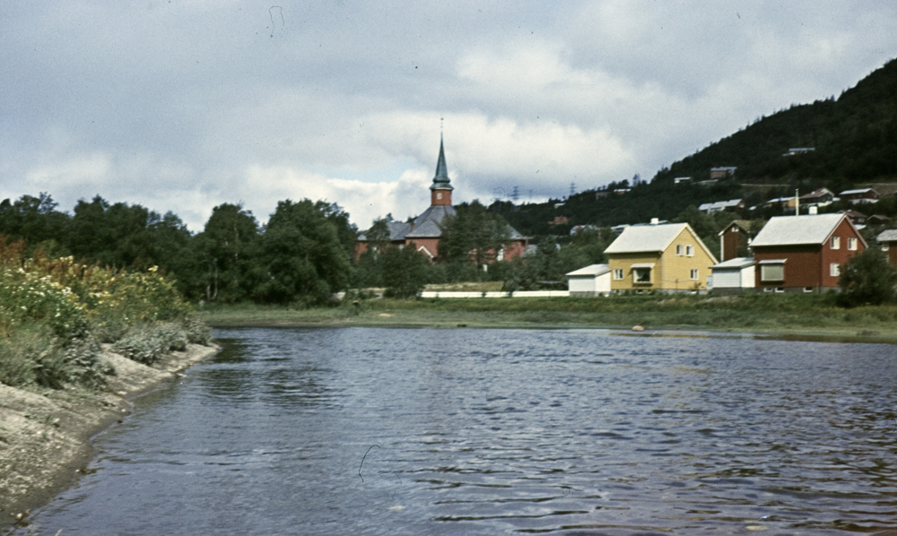 Motiv fra Skjerva med Dolstad kirke i bakgrunnen. Vi ser også Austerbygdveien 2 (gult) og 4 (rødt).