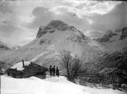 Vinterlandskap på fjellet, med tre mennesker stående utenfor