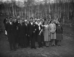 Bryllup, Brudepar med bryllupsgjester står ute ved bjørkelun