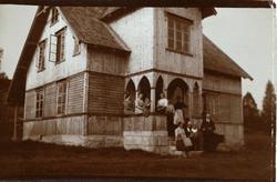 Gruppe på trappa til trebygning med bueportal over inngangen