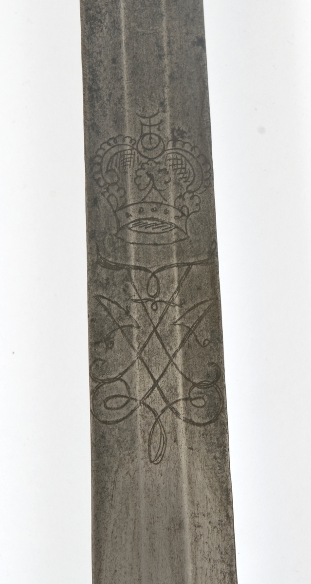 Messingfeste, med støpt nakkestykk med bølget dekor som går over i knappen.  Grept har snodd messingtrådsbevikling,.
Rette parerstenger, hvorav den bakre ender i en dråpe.  Fremre parerstang går over i håndbøylen Svakt oppbøyd skjell på utsiden med 7 fliker. Tre sidebøyler mellom skjell og håndbøyle. Tombøyle på innsiden.Festet har små skjedefjærer.
Tveegget rett klinge med sekskantet tverrsnitt Klingen er avkortet.
Etset F4 kronet speilmonogram.