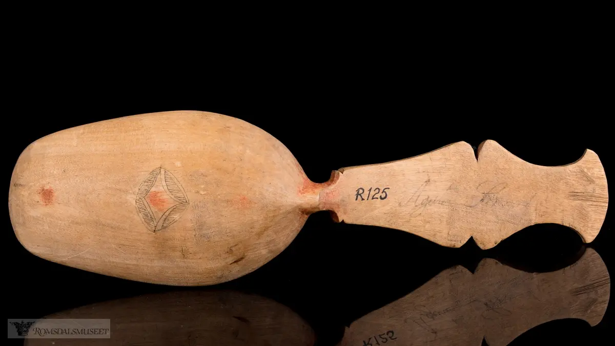 Stiliserte blad som er risset inn og fargesatt med mørk blå farge. Detaljer i rødt.