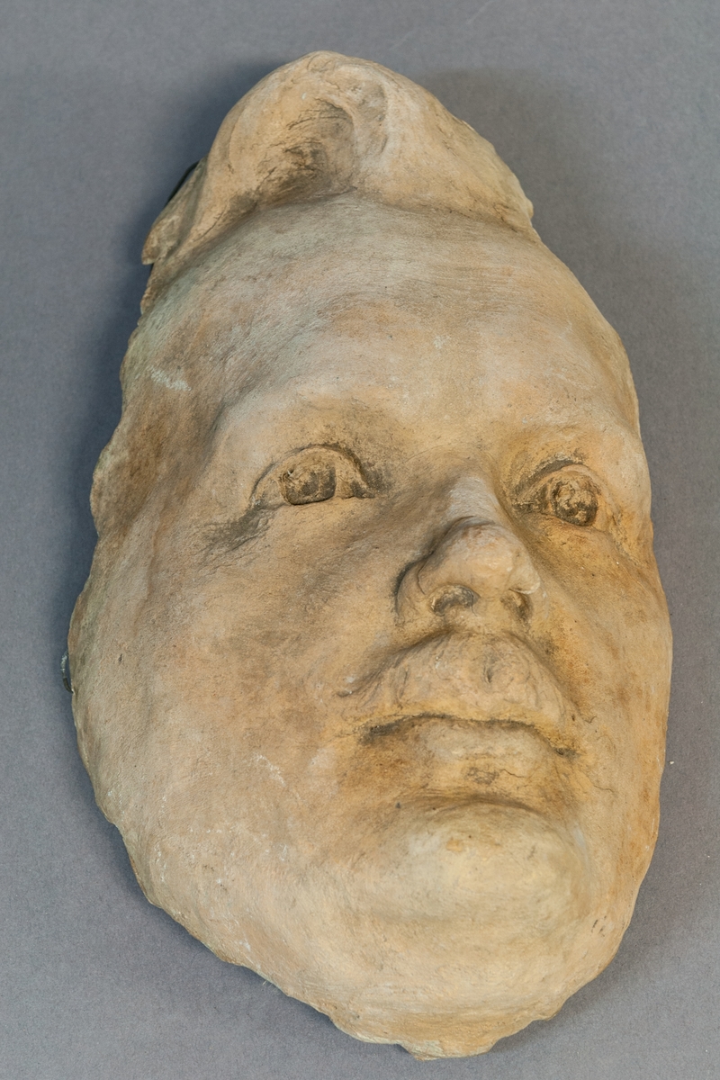 Ansikte i terracotta, med upphängning. Nathan Söderblom, skiss till bronsskulptur.