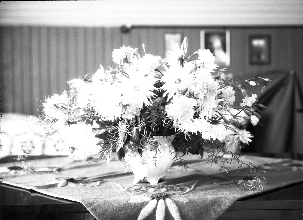 Karine Røisli ved et bord med blomster i en vase.
Tre bilder der to kun viser bordet med blomstene.