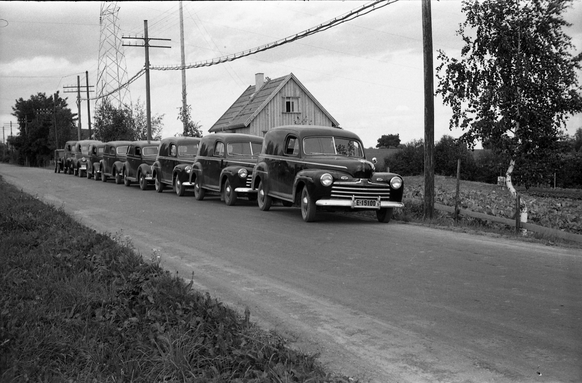 Tre bilder av en "flåte" av tilsynelatende nye varebiler.  Bilene er linet opp på vegen utenfor og foran boligen til Per Hovengen mellom Lillo og Lena. Personene på bilde nummer tre er ikke identifisert. Det dreier seg muligens om biler benyttet av ambulerende margarinselgere. Juli 1948.
Bilene skal iflg. informant være av følgende merker/modeller (bilde nr. tre som referansen): Fra venstre Tre amerikanske Ford 1946, to Ford V8 1938 stamdard, Ford V8 1937, Chevrolet 1946 Ford 1946 (de tre siste bygd på lett lastebil understell), og en ukjent førkrigsmodell, trolig ca. 1930.