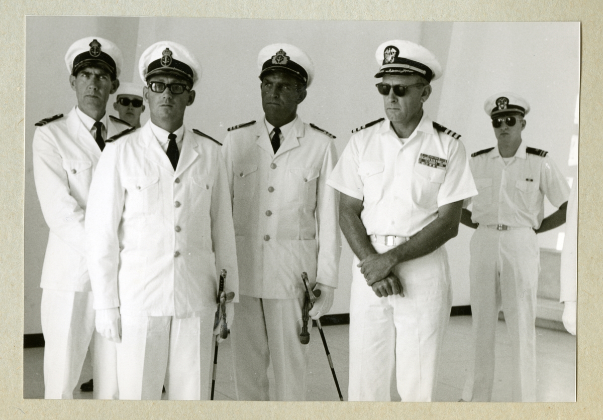 Bilden föreställer en grupp officerare i vita uniformer vid minnesmonumentet över attacken mot Pearl Habour på Hawaii. Längst till vänster i bilden står Oskar Linde. Fotot är taget under minfartyget Älvsnabbens långresa 1966-1967.