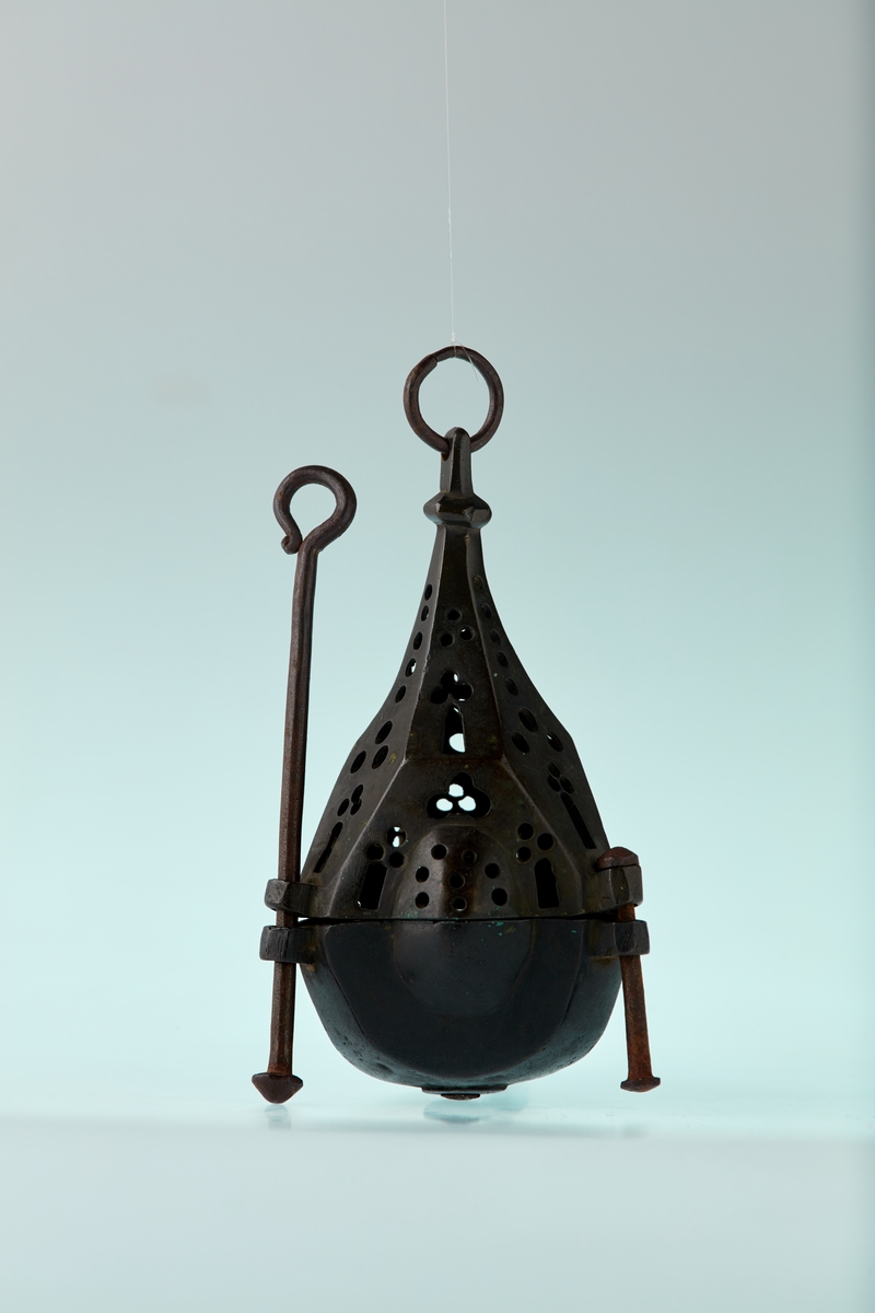 Bronse. 6 sidet. 3 av sidene med kuleformet utvidelse. Skål med pipe i centrum. Firpassformen viser hen på slutten av middelalderen. Den skjematiske og grove utførelse tyder på hjemlig produksjon. Ligger nær å gjette på Tunsberg. Etter reformasjonen er en lysepipe satt inn. Mulig denne lysestake har hengt etter en snor og likeledes den lange glidestangen