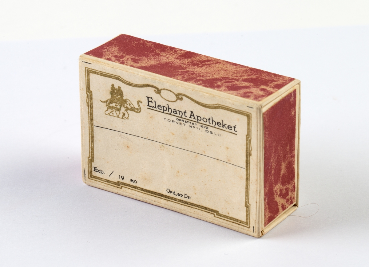 Firkantet pappeske. Uten innhold.
Logo til Elephantapotheket. Eske med skyvelokk.
