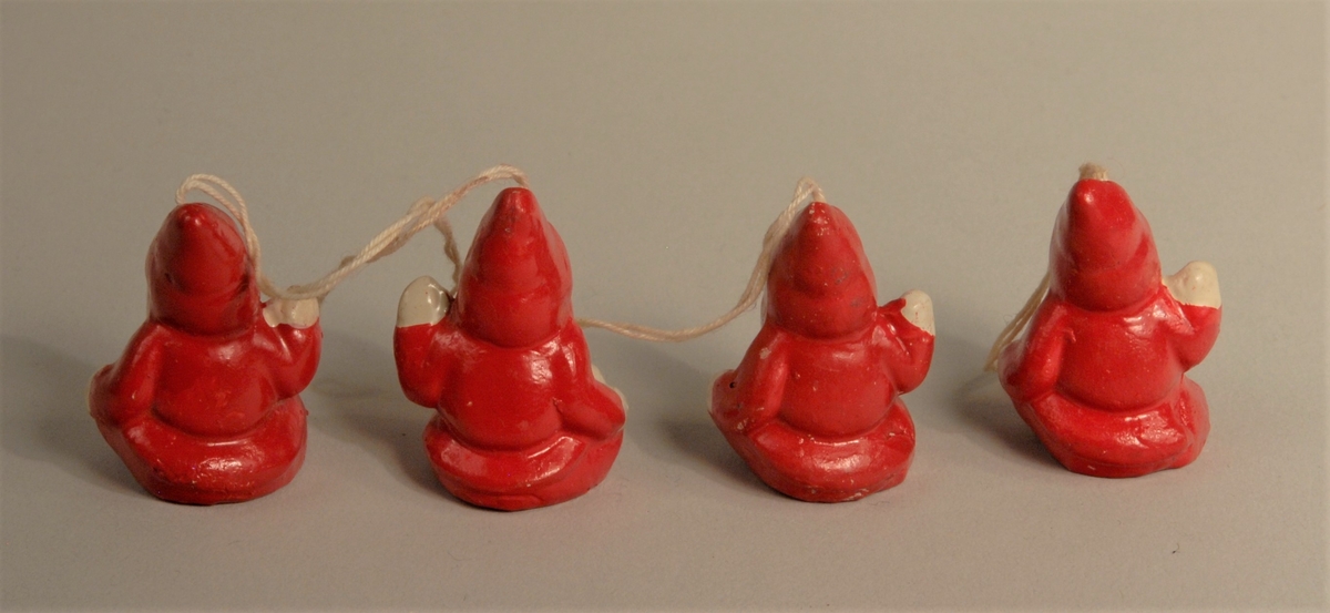 Handmalte nisser i rødt og hvitt. Tråd festet på toppen. Til å henge på juletreet. Nissene sitter og vinker med den eine hånda. Har rød topplue og rød dress.