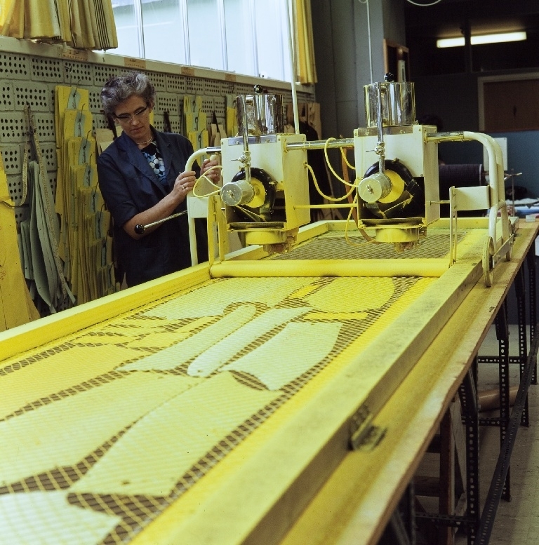 Ansatt i konfeksjonsfabrikken til Jonas Øgænd Sandnes lager skjæretegninger med en fargemaskin. Skjæretegningen kommer fram etter påsprøyting av en gul fargestoff.