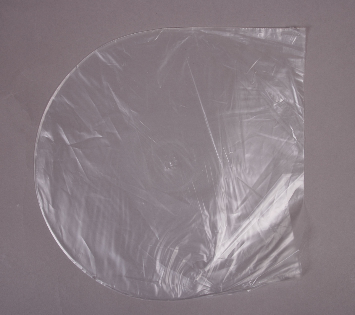 Grammofonplate i svart vinyl med en papirlomme som plateomslag. Plata ligger i en plastlomme.