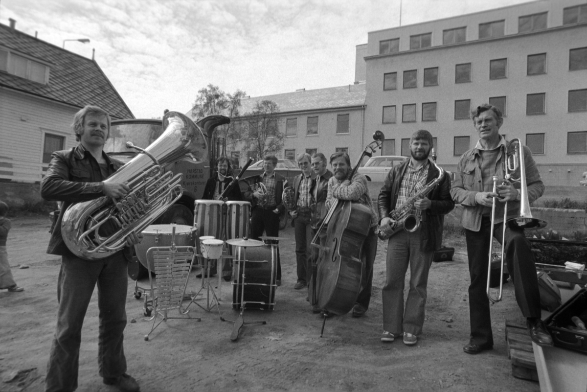 Gruppebilde av divisjonsmusikere med instrumenter, fotografert utendørs i sivil. Gammelsykehuset i bakgrunnen.