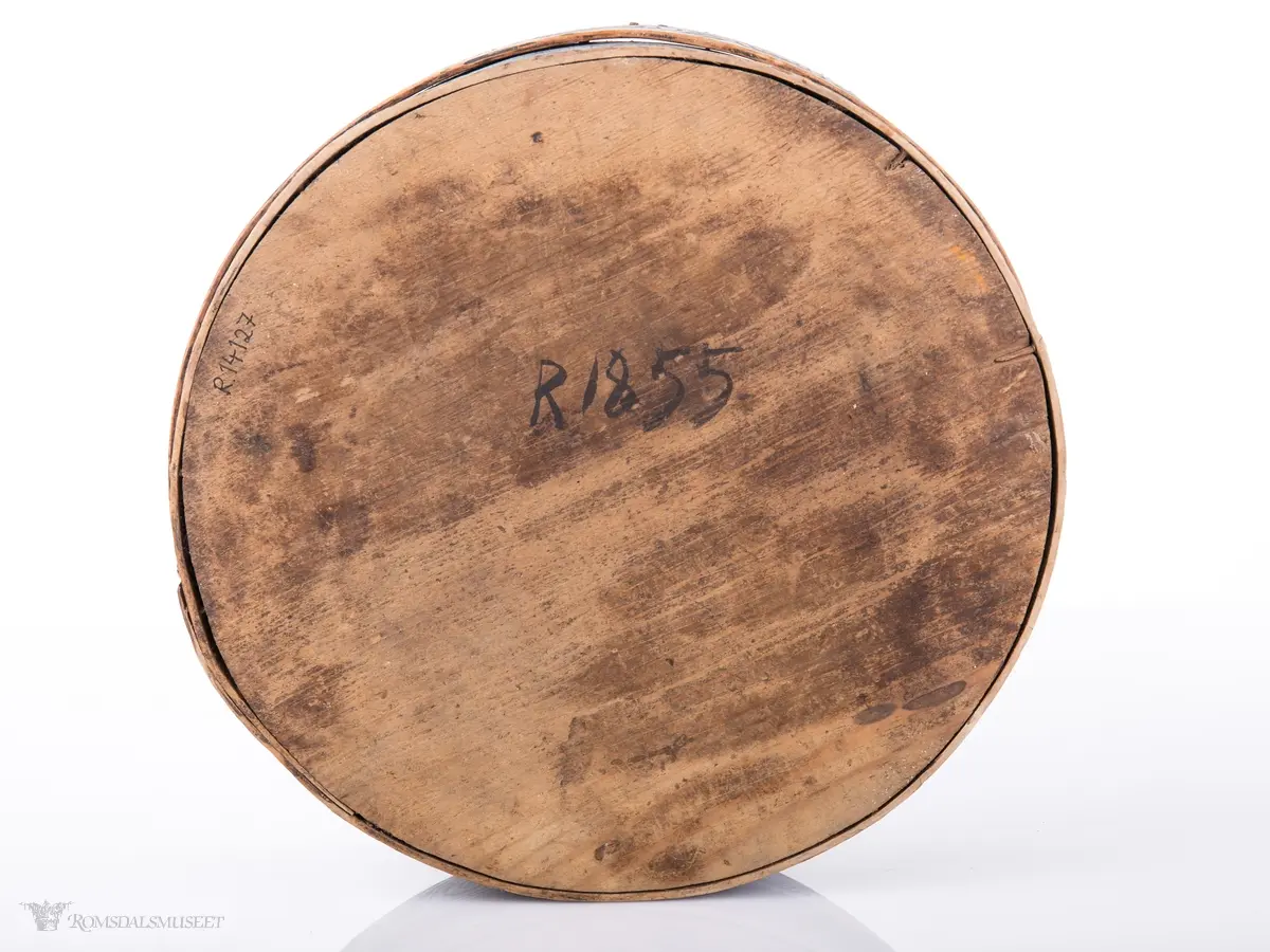 Seksbladsrose i karveskurd sammenkomponert med andre geometriske figurer sentralt på lokket. Dekorfelt rundt midten av lokket med kryss og spetter, N- formet bord o spetter ytterst. Lokktrosken har bølgeformede ranker. Små gjentagende blomsterbuketter på esketrosk. Innrisset passerrose i bunne  innvendig.