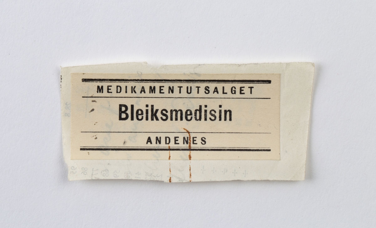 Etikett utklippet fra medisinpose. Hvit med sort skrift.