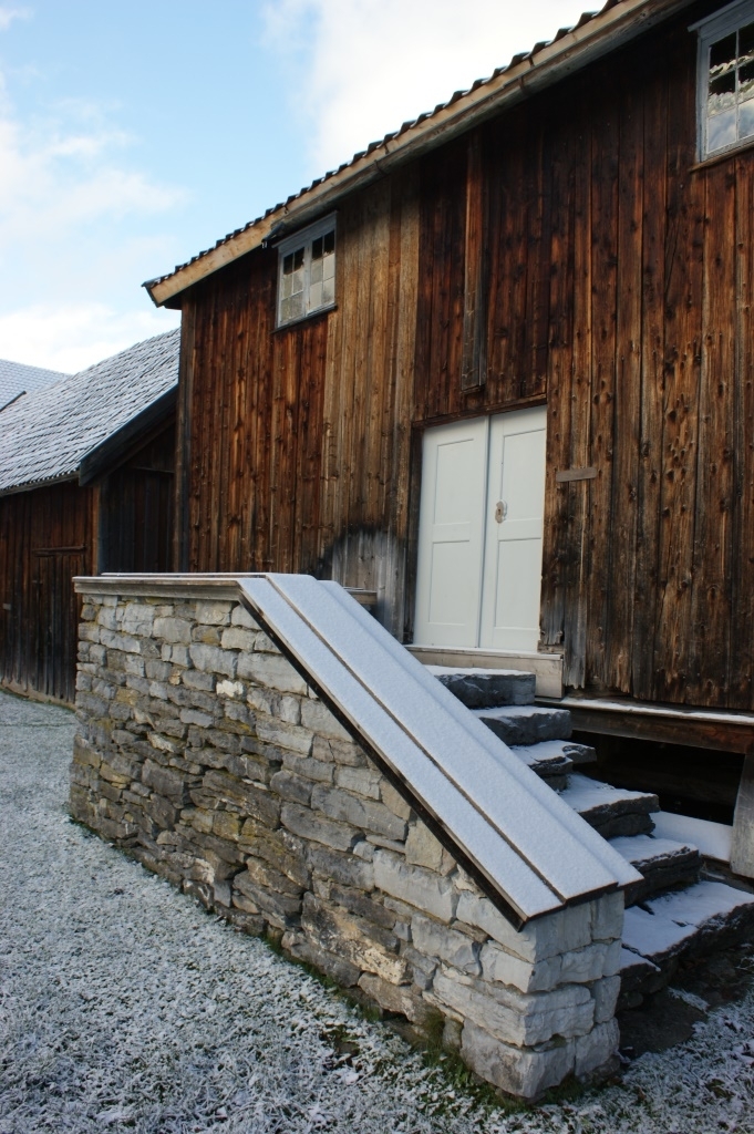 Laftet to-roms tømmerkjerne i to etasjer hvor tømmeret i andre etasje mot sør krager ut og etablerer en lukket langsval. Bygningen er utvendig panelt og gammelt malt med rød komposisjonsmaling.
To-rams vinduer med 6 ruter i ramma. Fyllings fløydør.
Bygningen er fundamentert med trestabber på en bæreramme av tre/grime som hviler på en tørrmurt ringmur av naturstein. 
Saltak - ombygd halv-valm. Åstak. Stående bordtro med flis undertekking. Taket er utvendig tekket med enkel-krummet teglstein. Steintrapp foran inngangssvalen.