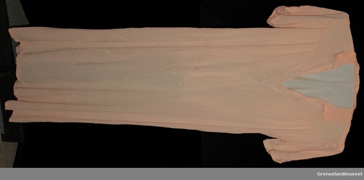 Lakserosa kunstsilke tricot, liten avrundet krave, Pyntet med maskinblonde rundt halsåpningen. Størrelse 46
