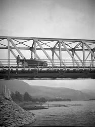 Bil på Randkleivbrua. En mann ved rattet, en sitter bak og e