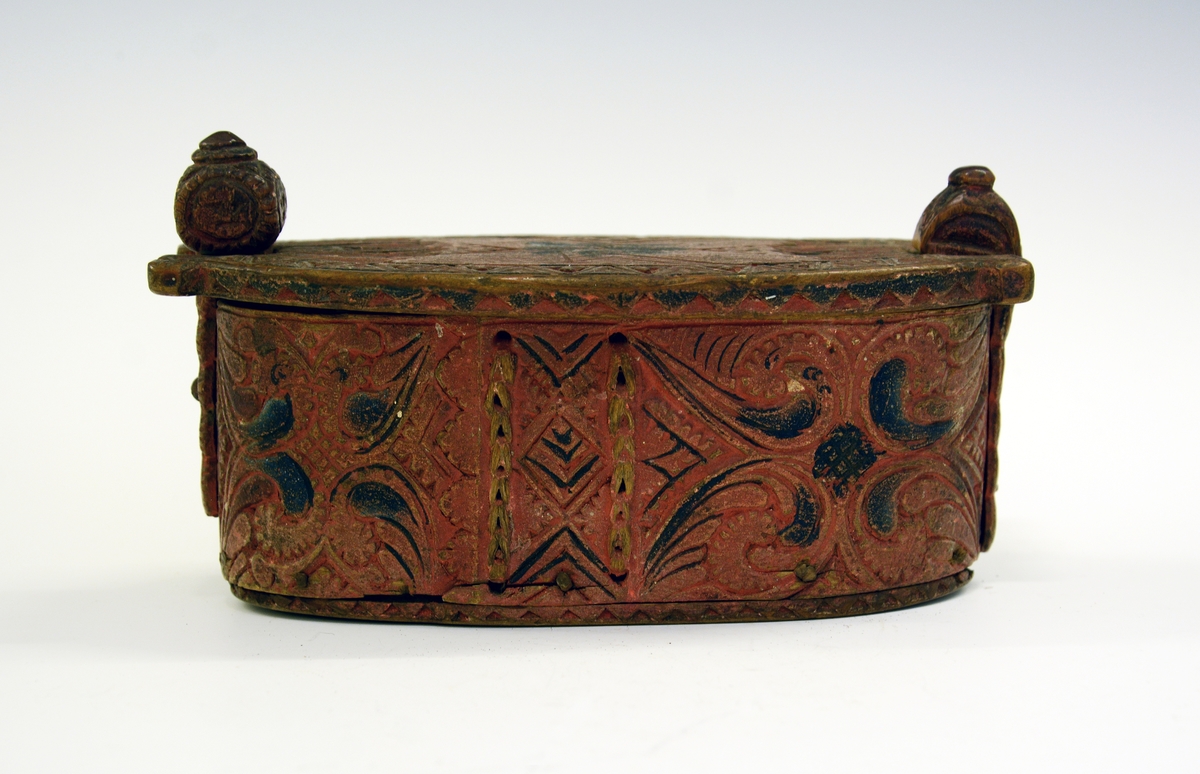 Tine av tre. Fra protokollen: Leikety-tine utskori i grovt kerbsnitt og plymrankkrullar. Under botnen skori 1814 og bokstavar. Standarane løglegt maksla som hovud med haarflettur. Raudmaala.