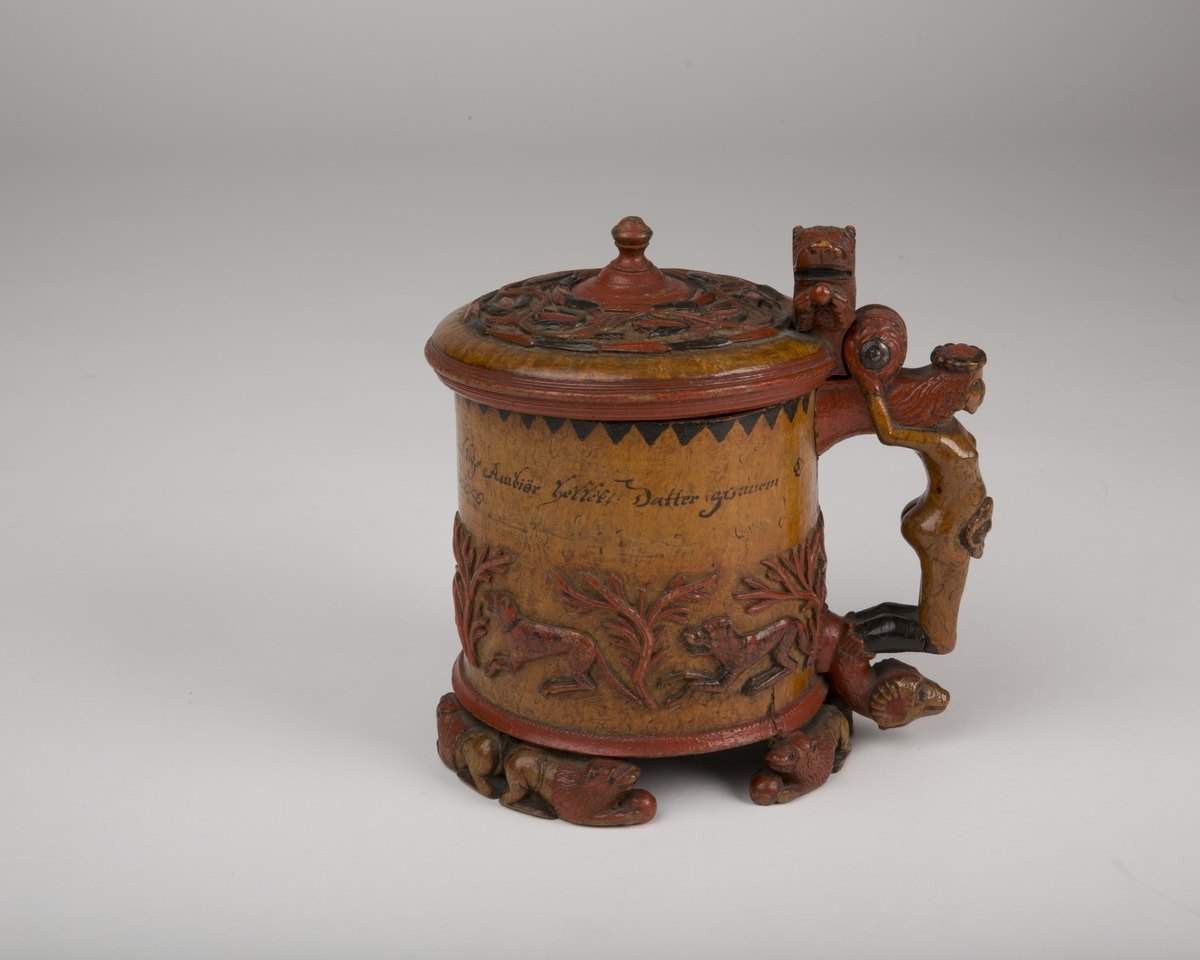 Dekorert med fortløpende billedfrise med dyr og trær på nederste del av korpus. Kannen har løveføtter og løvegjekk og bakkantine som håndtak. 