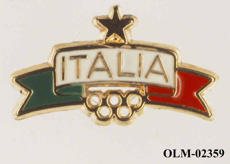 Utstanset merke med banner i grønt, hvitt og rødt med tekst på de hvite feltet. En stjerne over banneret og de olympiske ringer under.