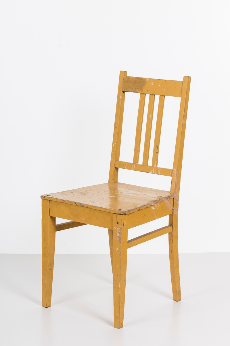 Stol i treverk, malt. Rygg med spiler. Den ene stolen har vært brukt betydelig røffere enn den andre.