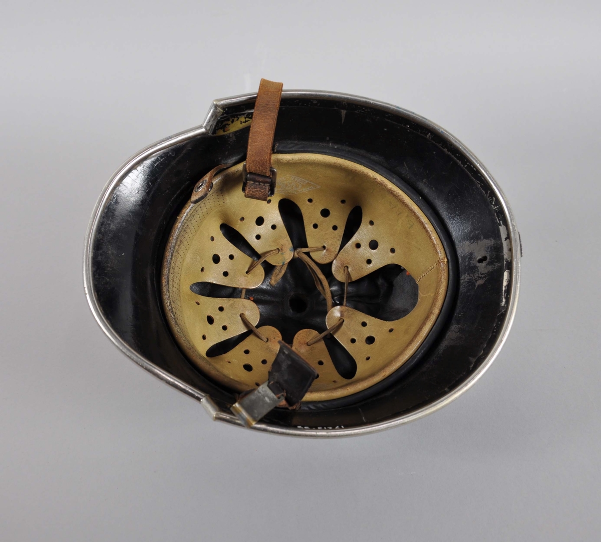 Blå brannhjelm av metall. Hjelmen har innerhjelm og hakereim av lær. På toppen er går det en opphøyd kant eller hanekam. På framsiden er emblem for det norske brannvesenet.