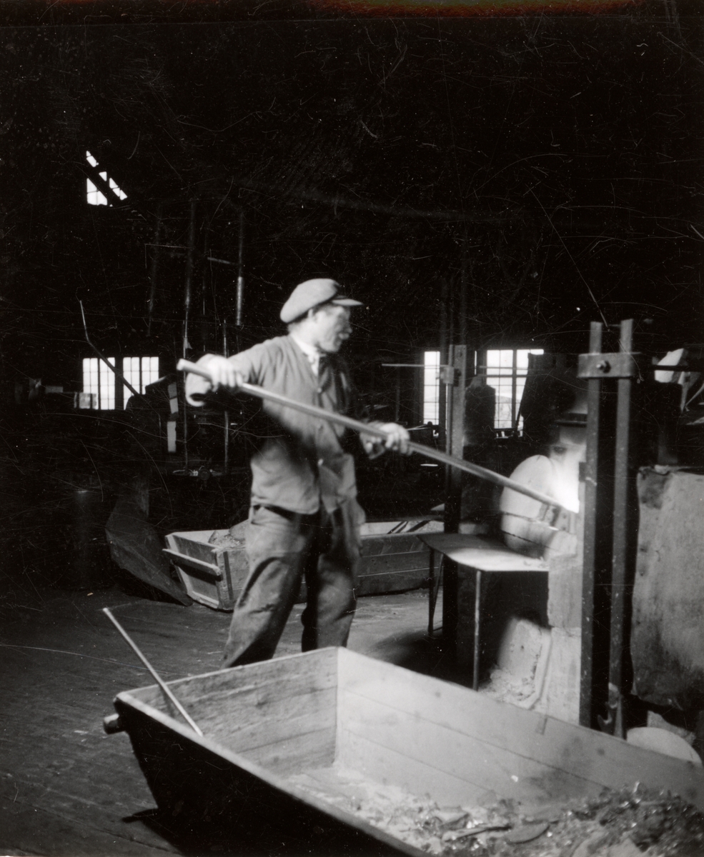 Gullaskrufs Glasbruk, Småland.
Fönsterglasblåsning i samband med filmning den 12 juni 1941. Hjälpsmältaren inlägger mängd i degeln.