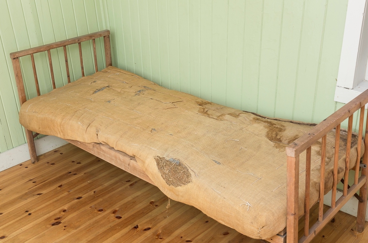 Sengeramme med sangegavler bestående av staver. Ubehandlet tre. Avstivere i metall. Nettingbunn.