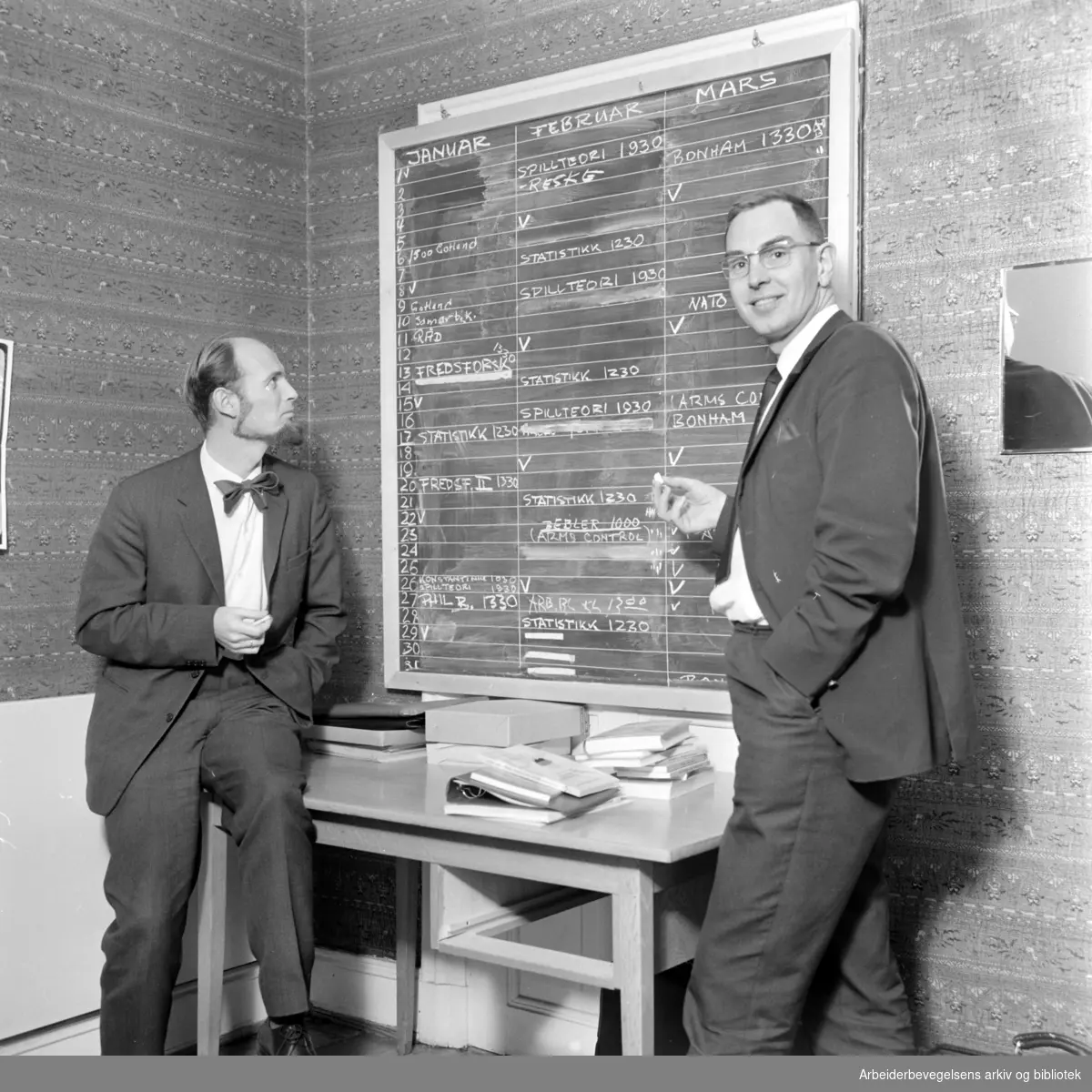 Utenrikspolitisk institutt i Parkveien. Olav Stokke og Per Frydenberg studerer tavlen, som forteller om dagsprogrammene ved Instituttet. Mars 1967