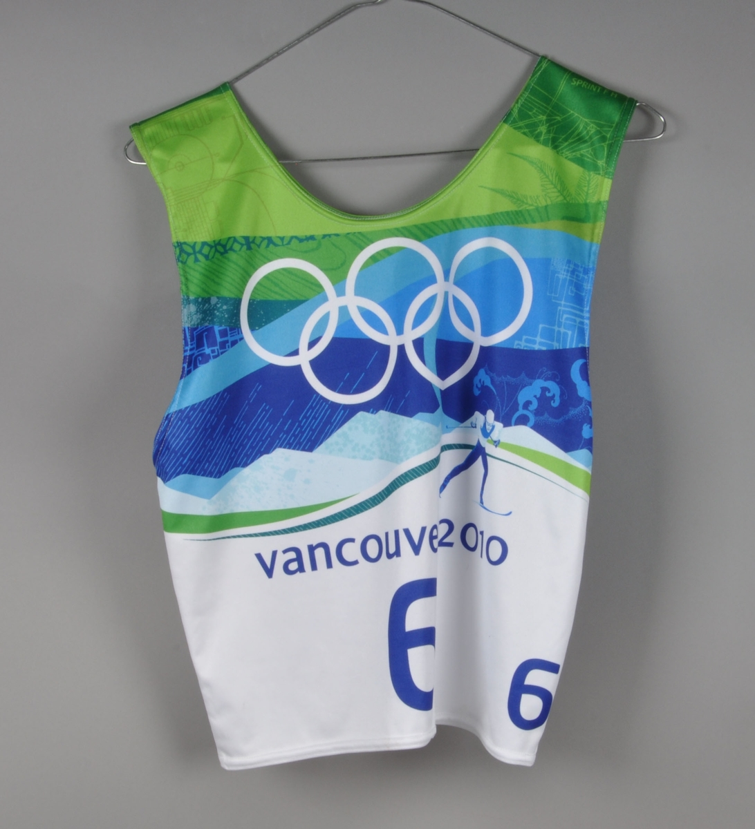 Flerfarget startnummer med nummer 6. Det er motiv av de olympiske ringene og en langrennsløper med fjell i bakgrunnen. Startnummeret er signert av Northug.