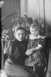 Gruppe. Voksen kvinne sitter med lita jente ca. to år, på fa