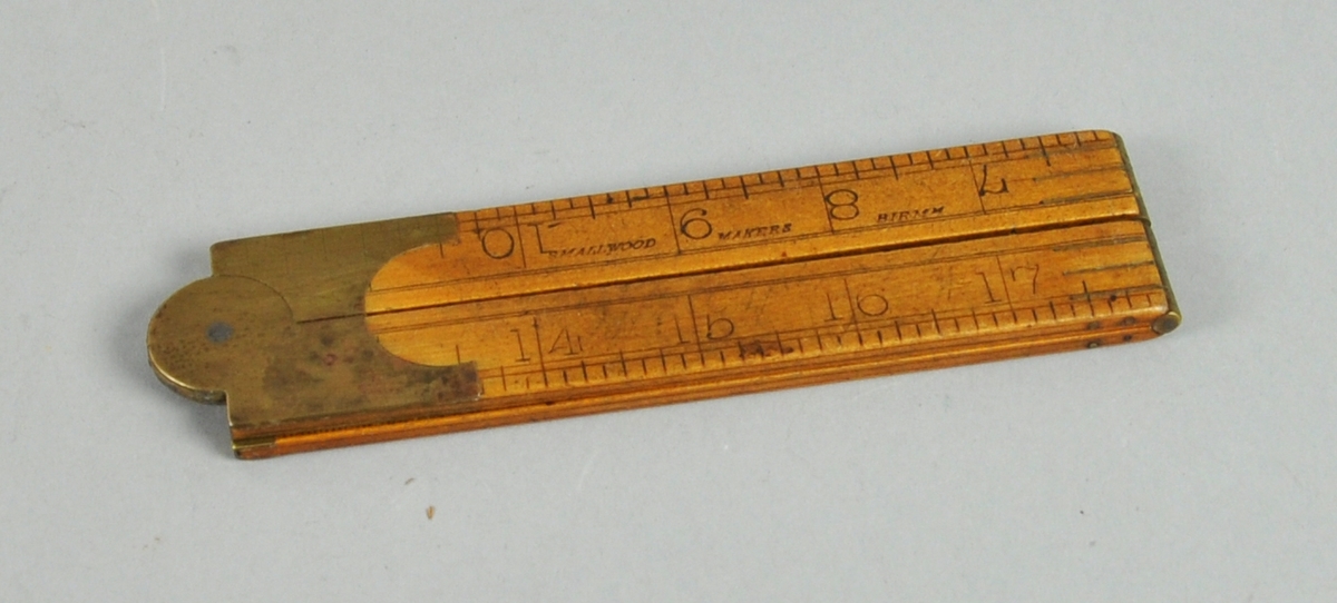 Sammenleggbar tommestokk av tre og metall med både cm og tomme som måleenheter.