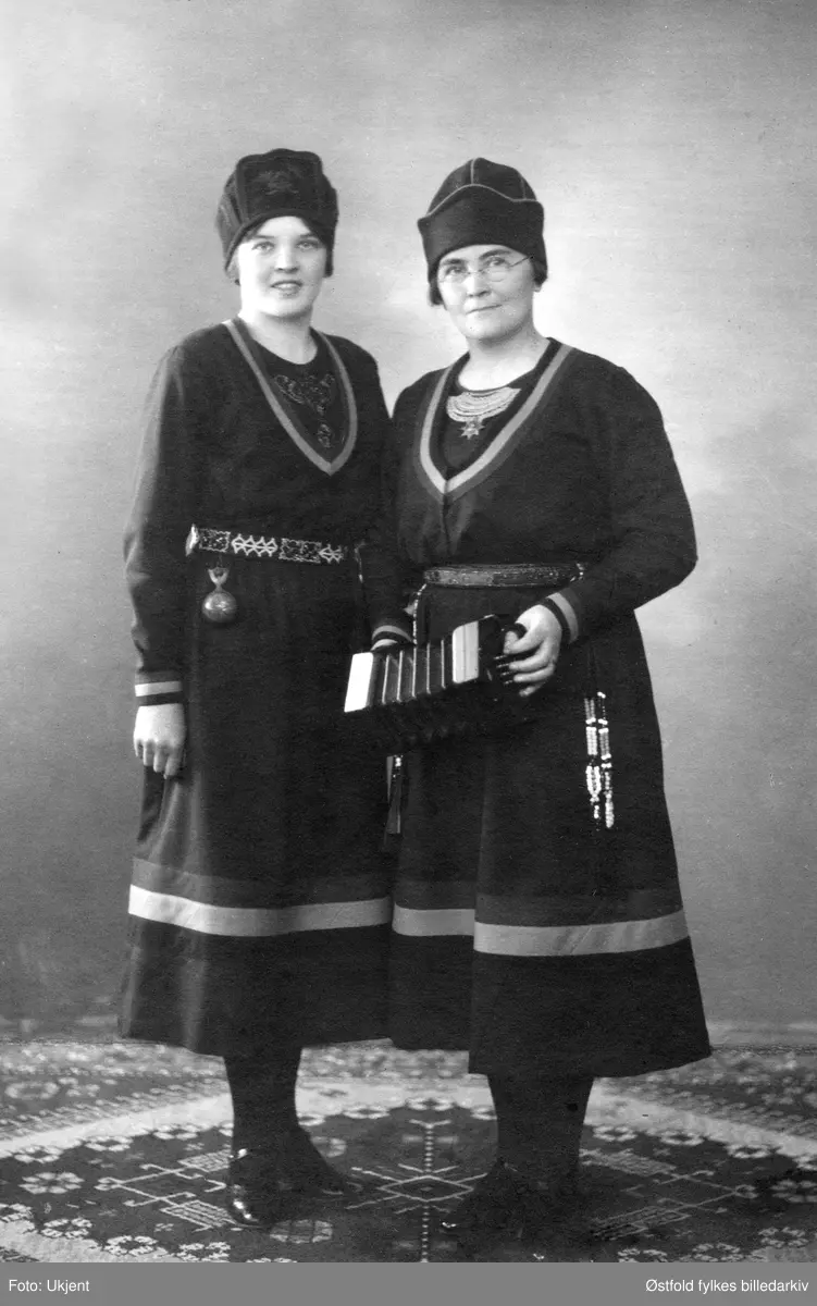 Studioportrett. To ukjente kvinner i samisk drakt.
Instrumentet er en concertina med English System.
Concertina var et instrument som gjerne ble brukt av sjømenn (lett å ta med seg). Det ble  utviklet i England 1829 (Sir Charles Weatstone), opprinnelig med tanke på at det kunne bli et konsertinstrument. Men det gikk fort over til å bli et folkemusikkinstrument.