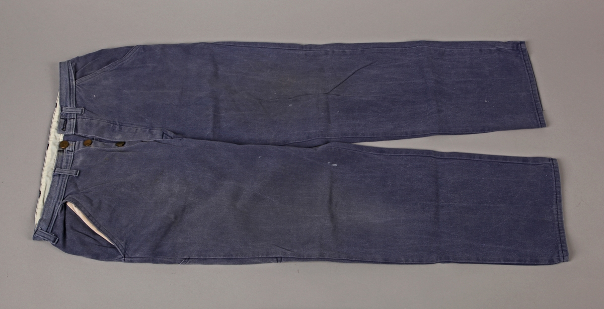 Tydeleg bruka og vaska blåtøysbukse. Fabrikasjonsmerke trykt på venstre lomme, men teksten vaska bort, - truleg Øglend