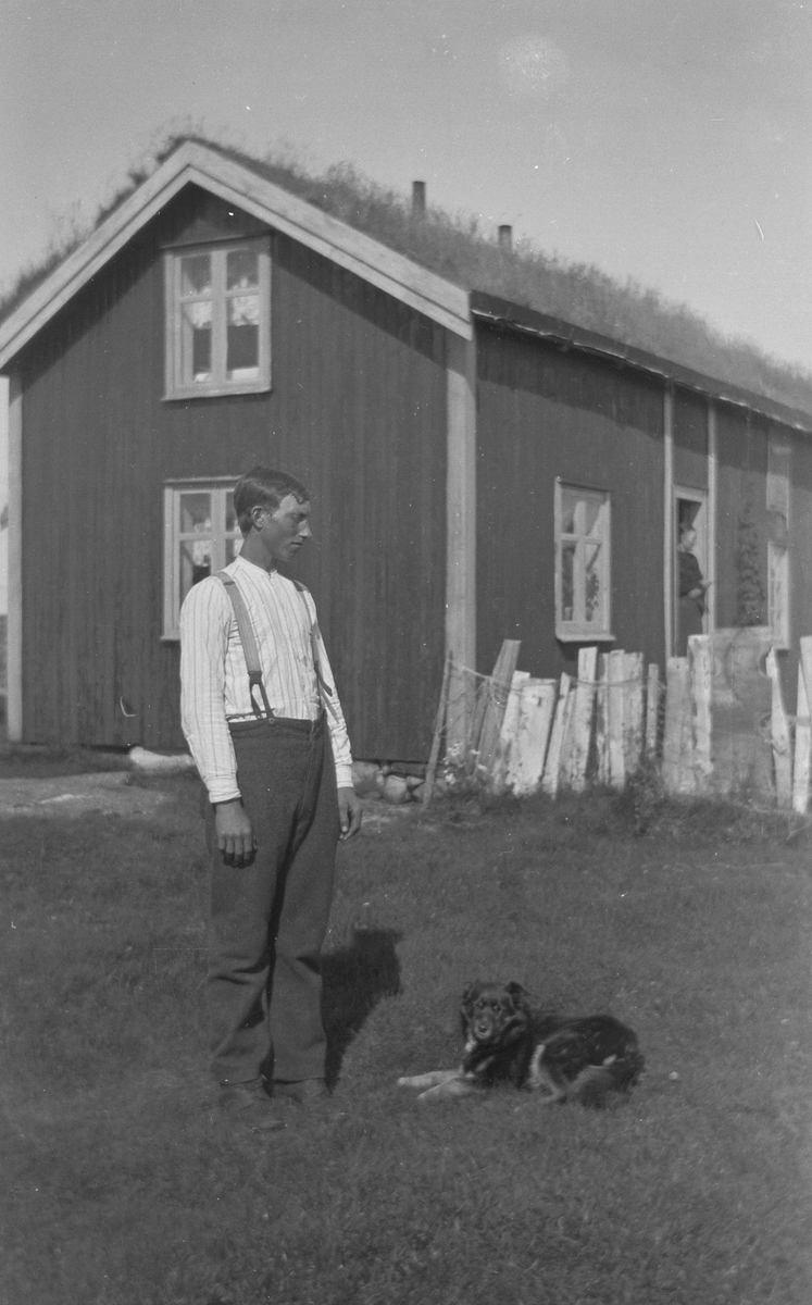 Mann og hund foran hus.