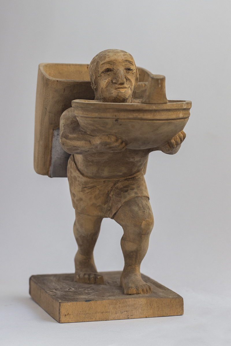 Treskulptur av mann med grautfat og kont.