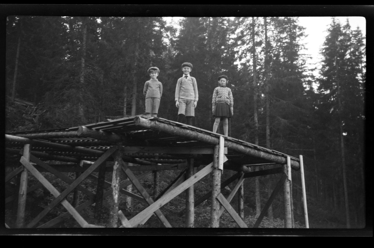 Tre glade barn på kanten av skihoppet ved Ørfiske i Nittedal. Fra venstre Rolf Sundt Jr., Julius Sundt og Elsa Sundt. Fotografert 1929.