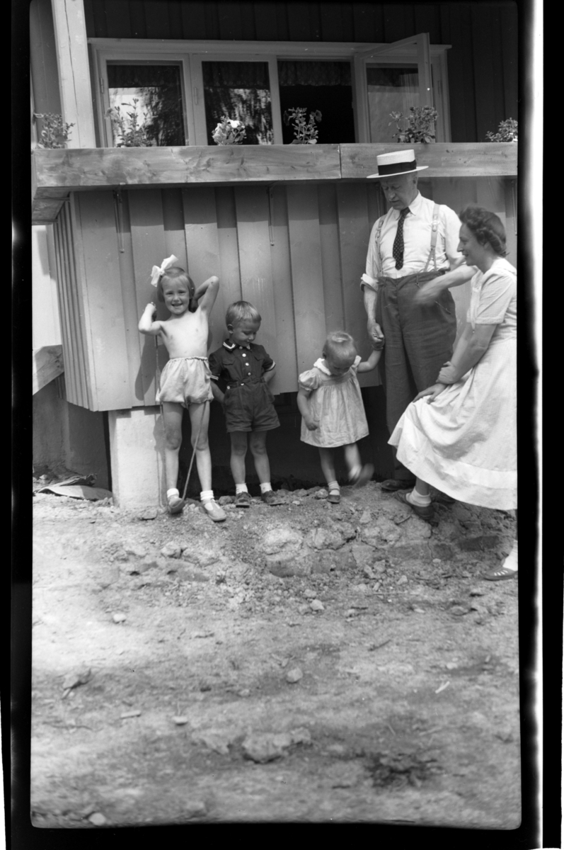 Rolf Sundt Sr. med svigerdatter Liv og barnebarna Ellen, Finn og Kirsten foran huset i Holmengrenda i Oslo. Fotografert 1949.