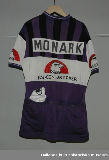 Cykeltröja i vit och lila syntet märkt: "MONARK". Tre fickor på ryggen, märkt: "MONARK" och "FALKEN DRYCKER" på både fram- och baksida. Även "Falkens" logotype på ärmarna.
Med tillhörande monarkkeps och en handske i bakfickor på tröjan.