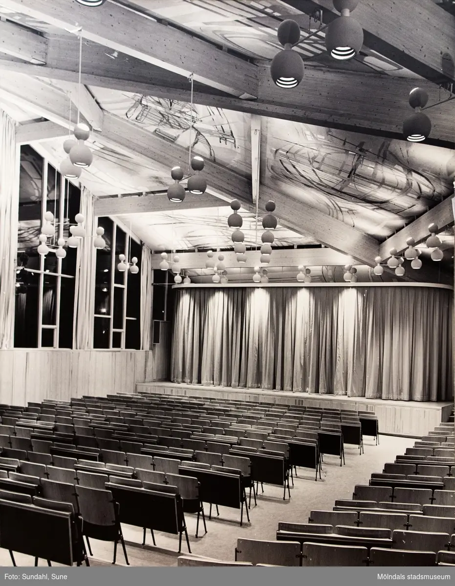 Interiörfotografi av Fässbergsgymnasiets aula i Mölndal, ca 1963-1966. Arktitekt är Jan Wallinder. I taket ses målningen "De fyra vindarna" av Leif Knutsen.