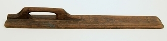 Platt mangelbräde med profilerade kantavsatser. Handtaget är skuret ur samma stycke som brädet. På brädet fins inskuret en tvärgående slinga.
