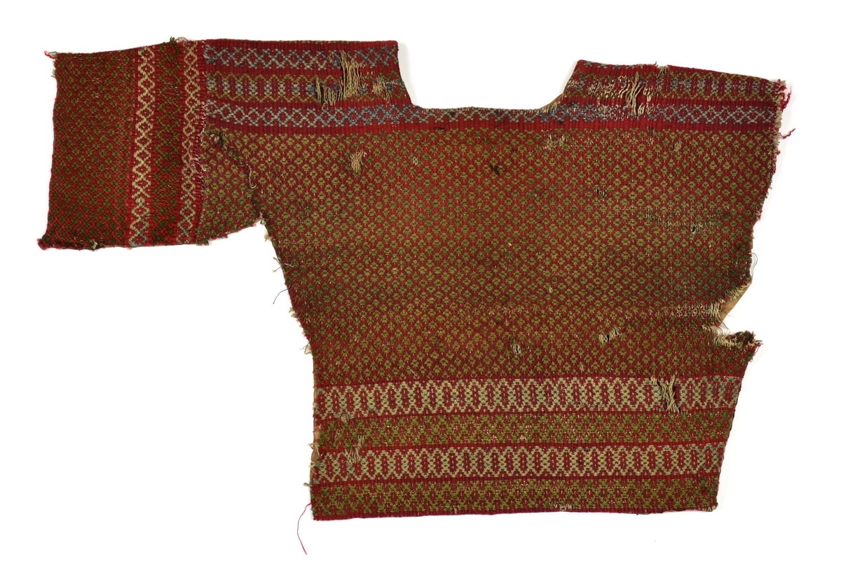 Fragment av tröja vävd av hårdtvinnat ullgarn i rött, grönt och ljusblått (nu mestadels urblekt) och oblekt linnevarp. Föremålet består av tröjans ena sida med en arm. Armen är avklippt.