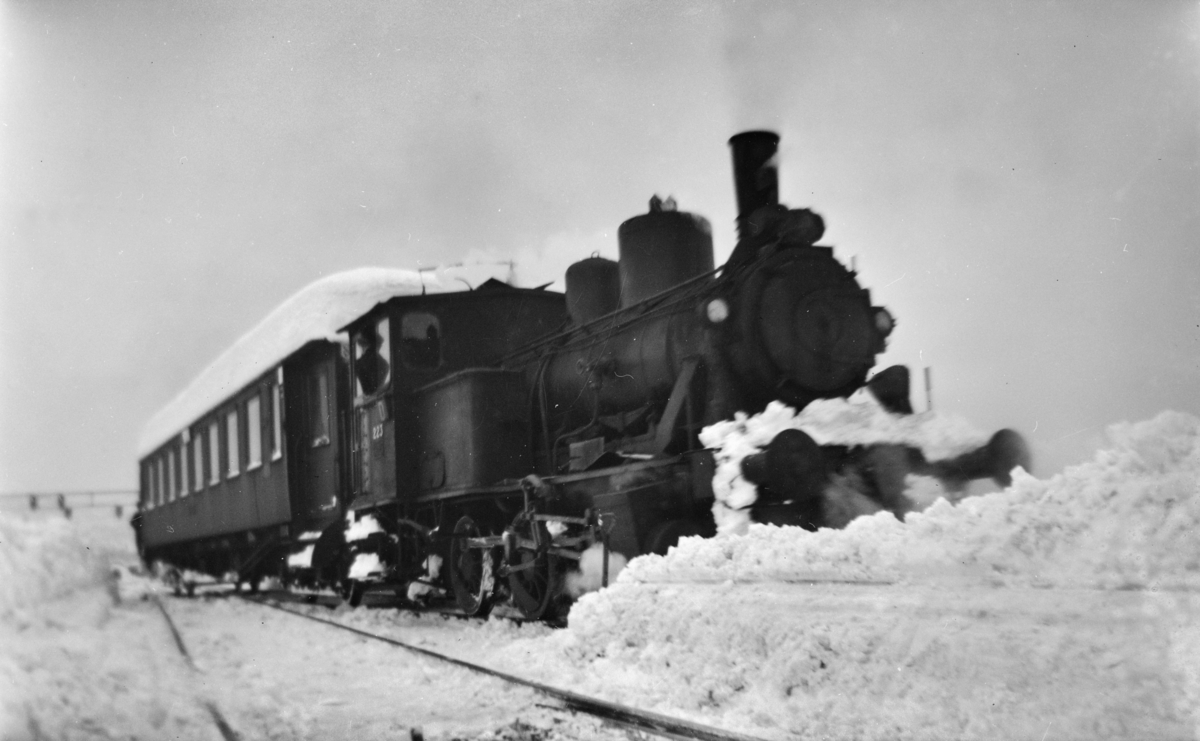 Snøryddingsmannskaper og snøryddingstog trukket av damplokomotiv type 25a nr. 223 på Trondheim stasjon.