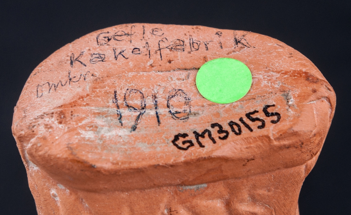 Statyett i bränd lera föreställande sittande hund, Mops. Oglaserad. Märkt under med blyerts: "Gefle Kakelfabrik omkr. 1910".