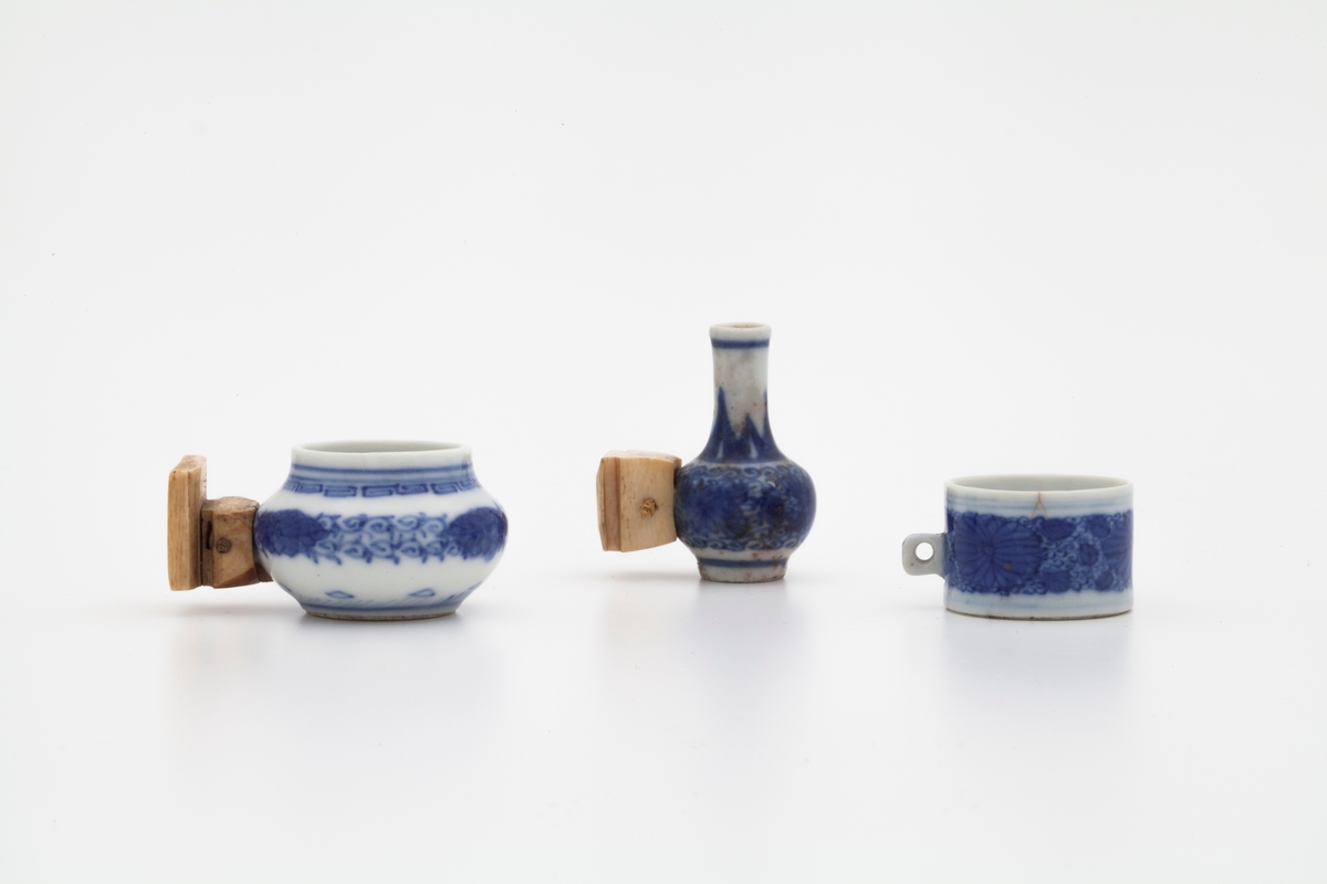 Tre fugleburkopper i porselen, dekorert med koboltblå underglasur. Fugleburkoppene har følgende former: vase, krukke og kopp.