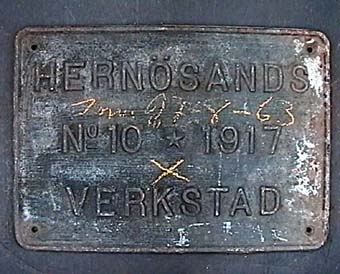 Rektangulär skylt av gråsvart gjutjärn:
"HERNÖSANDS
Nº 10 1917
VERKSTAD".