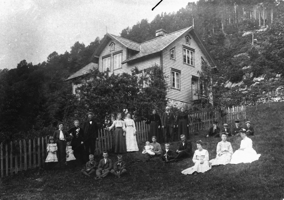Gruppefotografi av en familie i hagen utenfor et hus. Knut D. Stafset med familie ved gården Stafsetgjerdet (Klokkargjerdet).